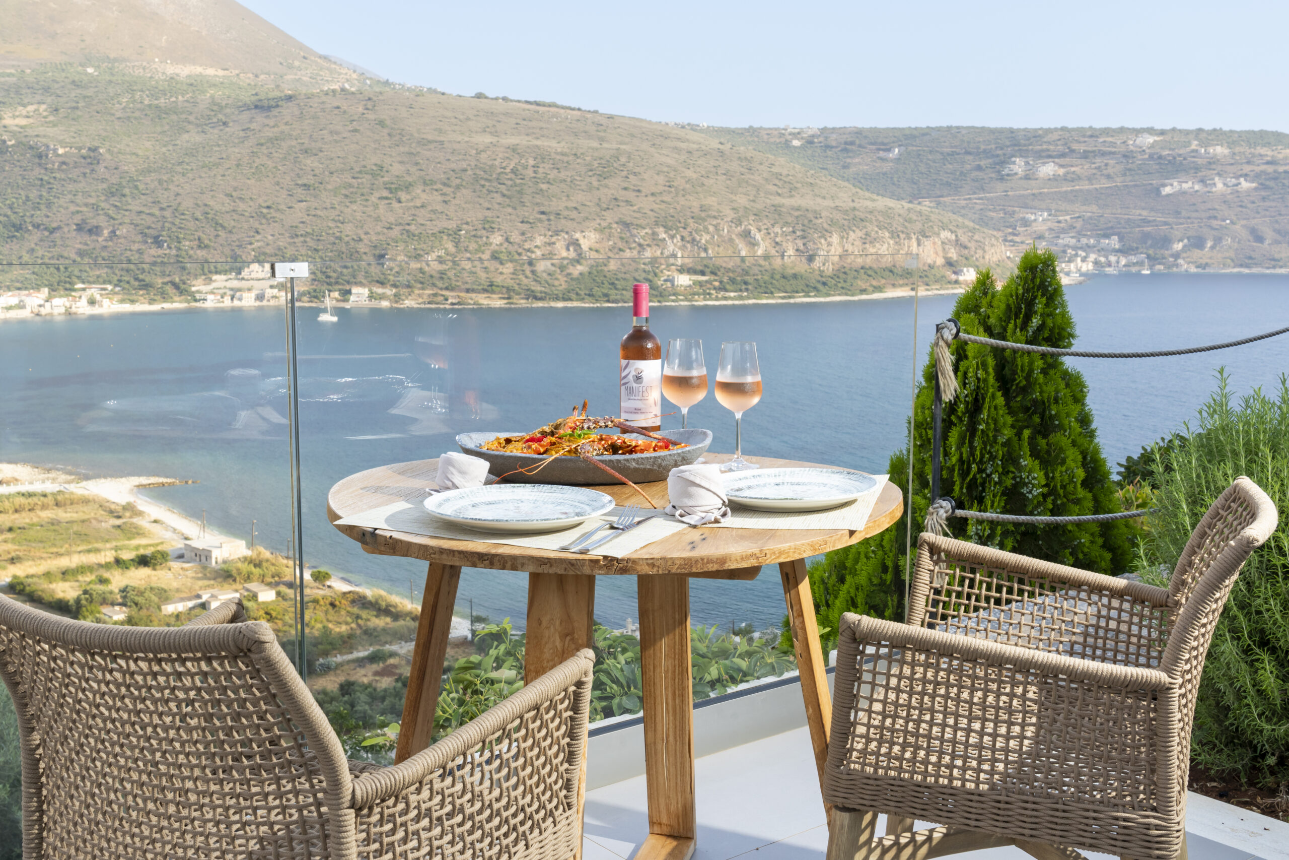Table set for two with rosé wine on a terrace overlooking Oitylo Bay, Manifest Boutique Hotel in Mani